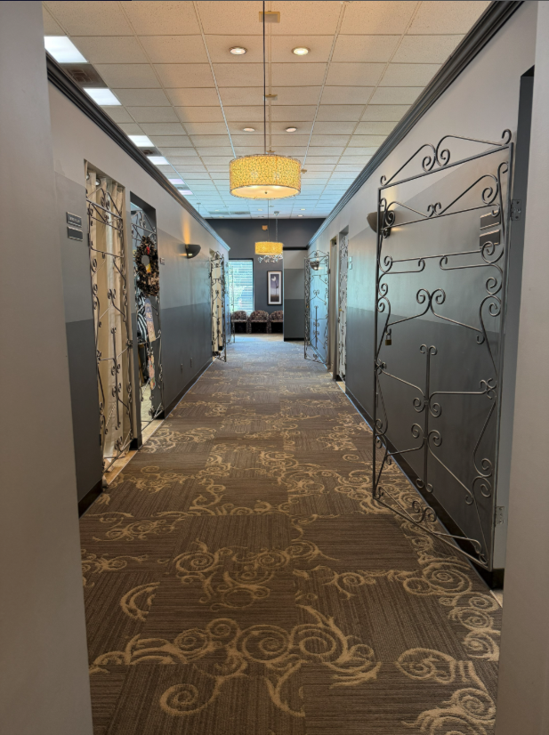 A gallery-style hallway of private stylist studios with wrought-iron doors at Blades Hair Design